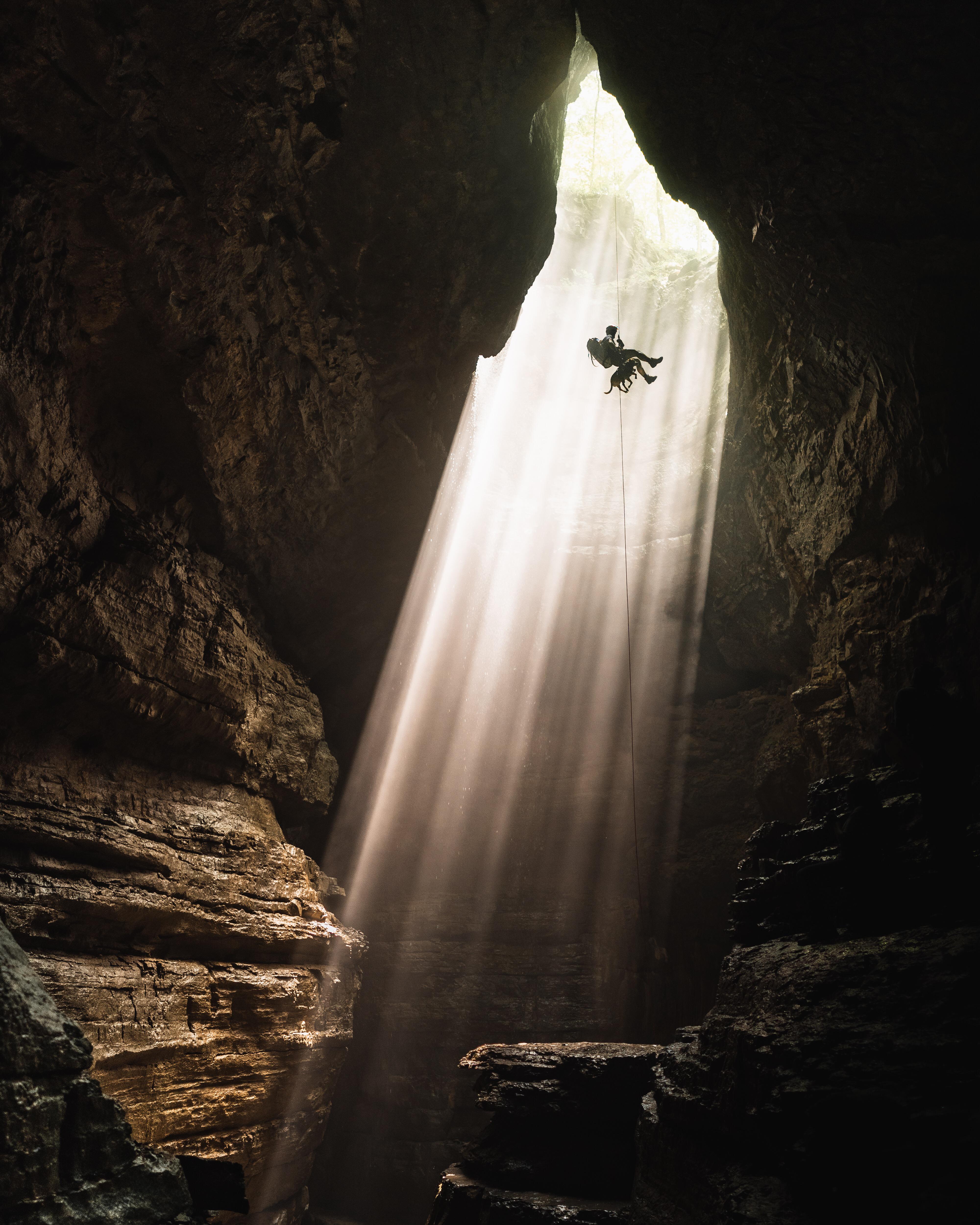 Caver Rapelling into Cave