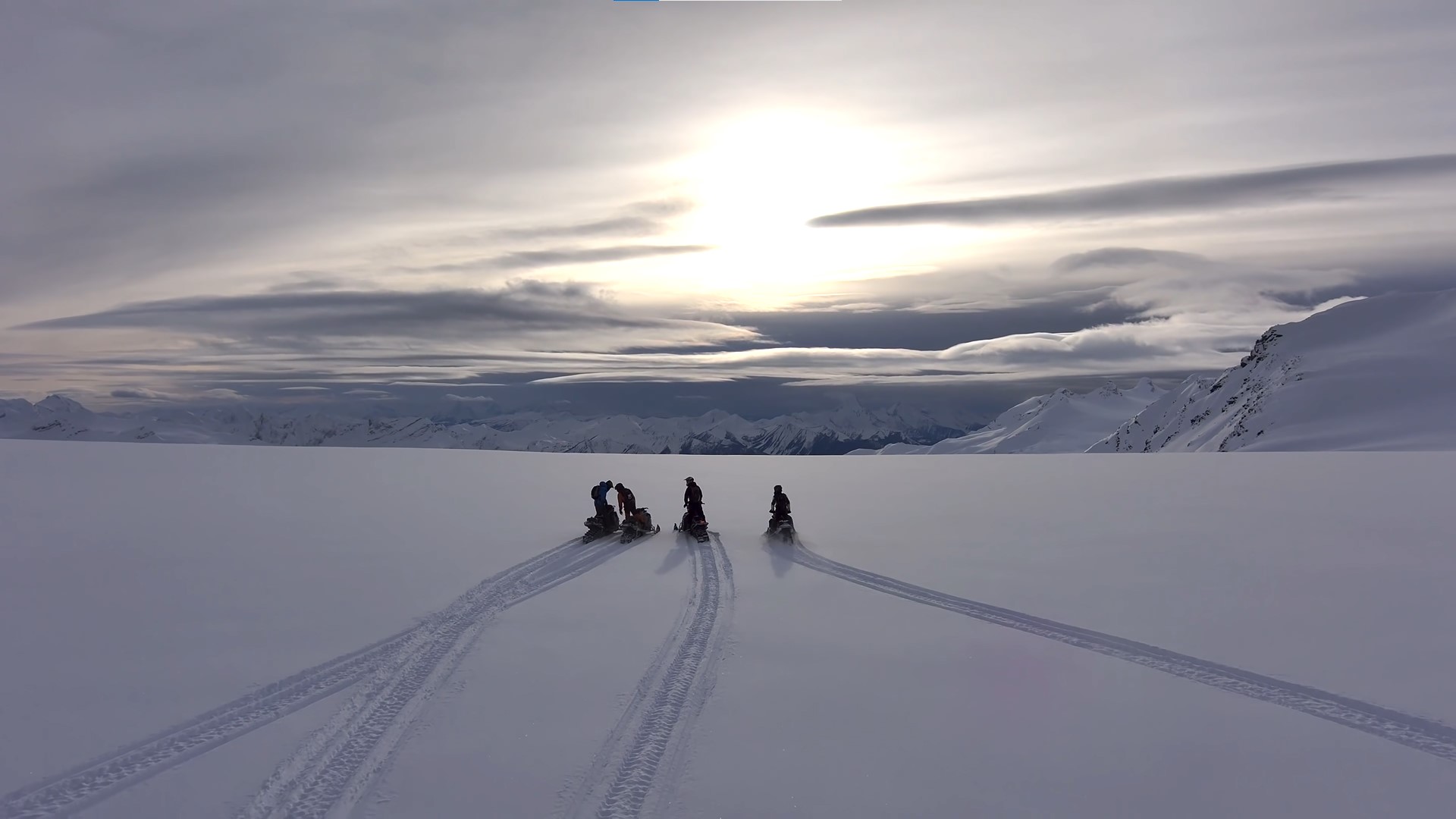 Exlorers on Snomobiles at Peak of Arctic Mountain